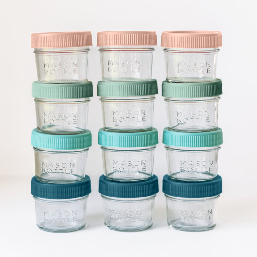 Set of glass jars with colorful lids stacked on a white background
