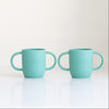 Two turquoise silicone sleeves for baby bottle on a white background