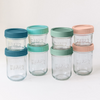 Set of glass jars with colorful lids on a white background