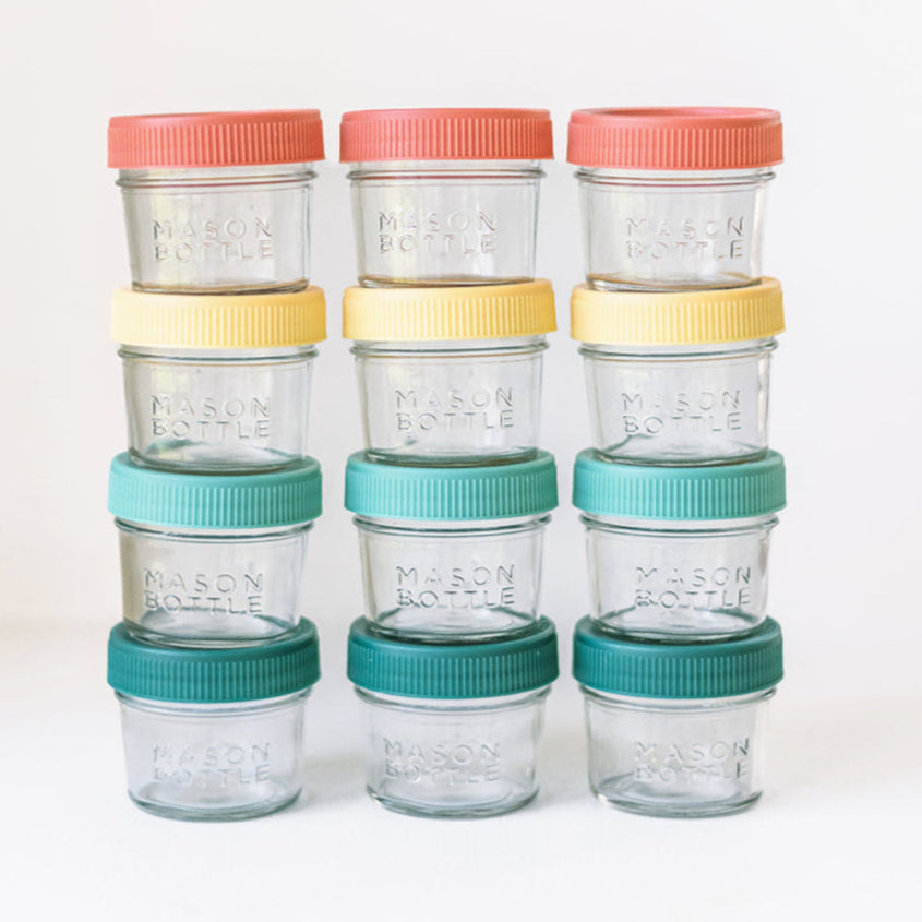 Set of glass jars with colorful lids stacked on a white background