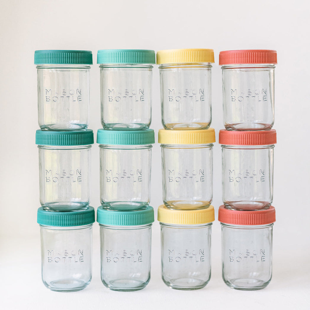 Set of clear glass jars with colorful lids on a white background